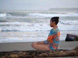 Women sits on beach and meditates